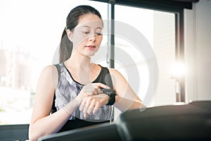 Beautiful asian woman running treadmill. smartwatch check pulse