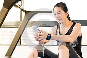 Beautiful asian woman running treadmill use smartphone listening
