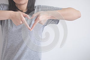 Beautiful Asian woman shows gesture heart with fingers on a white background with copy space.