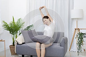 Beautiful Asian woman sits lazily on the sofa