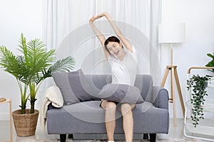 Beautiful Asian woman sits lazily on the sofa