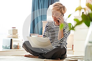 Beautiful Asian woman sitting on bed & working from home on laptop