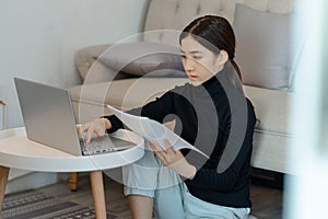 Beautiful asian woman sitting and calculating income tax in living room