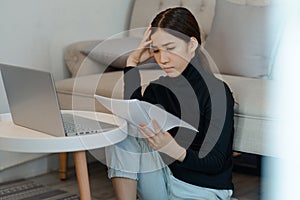 Beautiful asian woman sitting and calculating income tax in living room