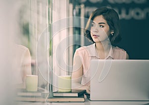 Beautiful asian woman sitting at desk and using laptop