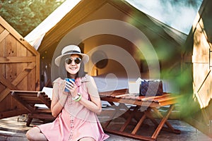 Beautiful asian woman sitting at tent and drinking coffee in the morning,Enjoys of resting time,Happy and smiling