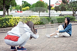 à¸ºBeautiful Asian woman with smartphone taking picture of her friend in an old city,lifestyle and people concept