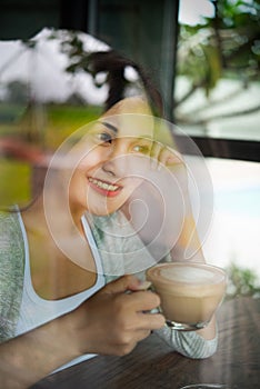 A beautiful Asian woman smiles happily with coffee in the restaurant. Lifestyle of young women during the relaxing time in the