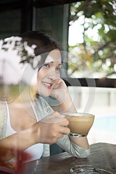 A beautiful Asian woman smiles happily with coffee in the restaurant. Lifestyle of young women during the relaxing time in the