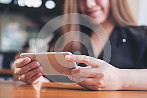 A beautiful Asian woman with smiley face holding and using horizontal smart phone to watching tv and playing games