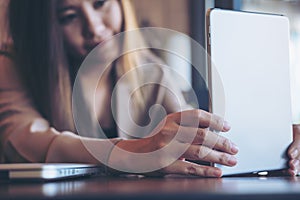 A beautiful Asian woman with smiley face holding and using tablet pc for take a picture