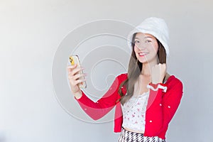 Beautiful Asian woman smilinhowho wears red coat and white hat as a Santy girl holds a smartphone in her hand and another act as