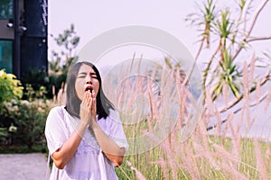 Beautiful asian woman sneezes because of allergy with flower at nature photo