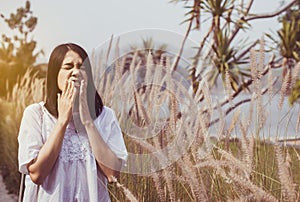 Beautiful asian woman sneezes because of allergy with flower at nature photo