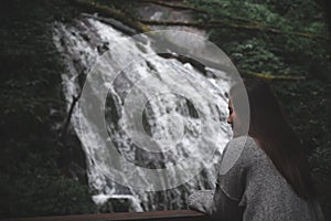 A beautiful Asian woman standing in front of waterfall in tropical forest