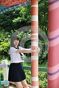 A beautiful Asian woman in student dress playing in an amusement park