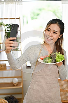 Beautiful Asian woman taking selfie of herself and her homemade salad. Healthy lifestyle