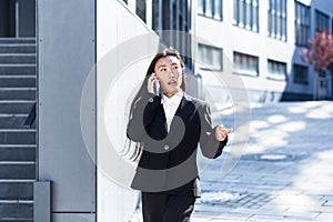 Asian woman talking on the phone, business woman on a break walking near the office