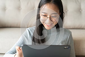Beautiful of asian woman touching keyboard on modern digital tablet, Asia girl smiling while working  in her home