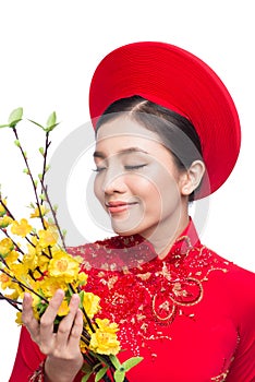 A beautiful Asian woman on traditional festival costume Ao Dai holding Hoa Mai tree Ochna Integerrima flower