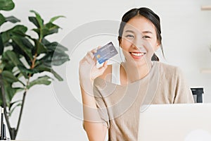 Beautiful Asian woman using computer or laptop buying online shopping by credit card.