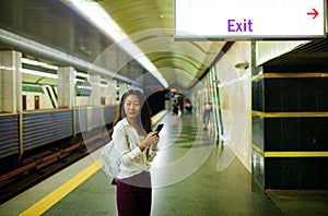 Beautiful woman using her cell phone on subway platform.