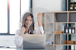 Beautiful asian woman using laptop computer, exciting and celebrating with good news of business successful. Small