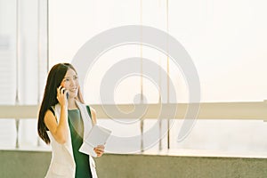 Beautiful Asian woman using mobile phone and digital tablet at modern office, business communication or smartphone technology