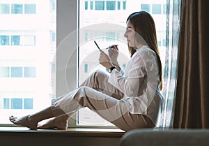 Beautiful Asian woman using smartphone while working the living room