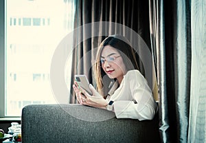 Beautiful Asian woman using smartphone while working the living room