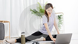Beautiful Asian woman watching yoga teacher and light exercises in her living room at home