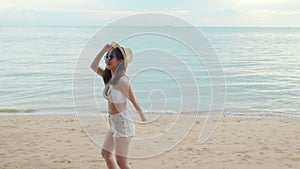 Beautiful Asian woman wear sungrass and hat turning back running to beach