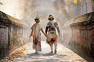 Beautiful Asian woman wear Thai traditional dress action of walking together with Thai classic masked from the Ramakien character
