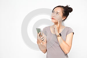 Beautiful Asian woman wearing grey casual shirt holding smartphone on white background and copy space.  Cute Asian woman is