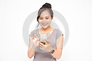 Beautiful Asian woman wearing grey casual shirt holding smartphone on white background and copy space.  Cute Asian woman is