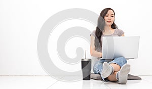 Beautiful Asian woman wearing grey casual shirt using laptop on white background and copy space. Cute Asian woman sitting on the