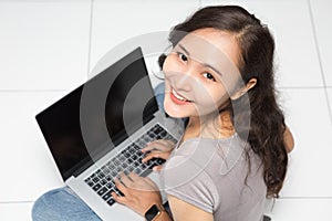 Beautiful Asian woman wearing grey casual shirt using laptop on white background and copy space. Cute Asian woman sitting on the