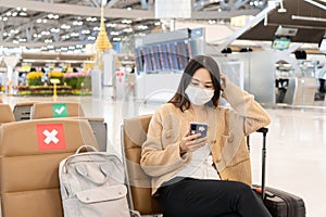 Beautiful Asian woman wearing medical mask to prevent infection from coronavirus. Social distance in public place. Seating