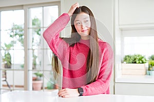 Beautiful Asian woman wearing pink sweater on white table confuse and wonder about question