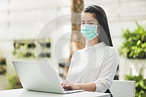 Beautiful asian woman wearing protection mask work from home in the morning. Young asian female with laptop stay at home