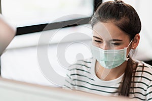 Beautiful asian woman wearing protection mask work from home in the morning. Young asian female working with computer stay at home