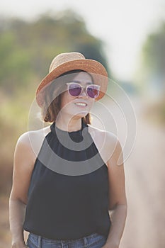 beautiful asian woman wearing straw hat toothy smiling with happiness standing outdoor against beautiful morning light