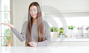 Beautiful Asian woman wearing stripes sweater smiling cheerful presenting and pointing with palm of hand looking at the camera