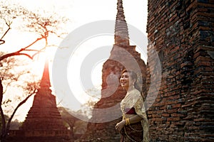 beautiful asian woman wearing thai tradition dress standing against brick wall at old temple of ayutthaya world heritage site of photo