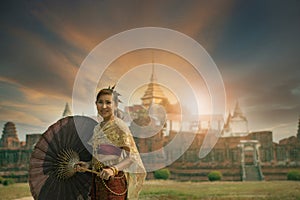 beautiful asian woman wearing thai tradition suit standing against old temple in Ayutthaya world heritage site of unesco central