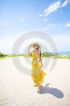 Beautiful asian woman wearing yellow clothes standing on sea beach against midday sun light