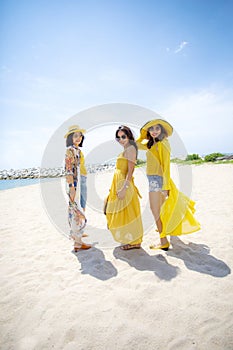 Beautiful asian woman wearing yellow clothes standing on sea beach against midday sun light