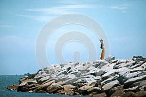 Beautiful asian woman wearing yellow clothes standing on sea beach against midday sun light