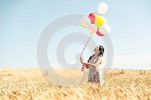Beautiful asian woman in a wheat field with air balloons