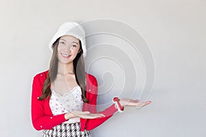 Beautiful Asian woman who wears red coat and white hat as a Santy girl acts her hand to present something on the white background